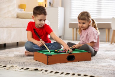 Cute brother and sister playing billiards at home