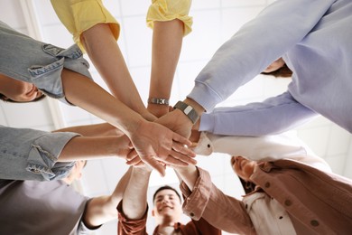 Unity concept. People holding hands together indoors, bottom view