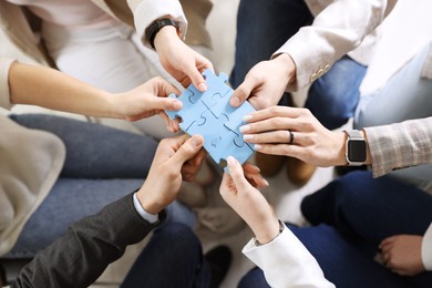 Photo of Unity concept. People putting puzzle pieces together indoors, top view