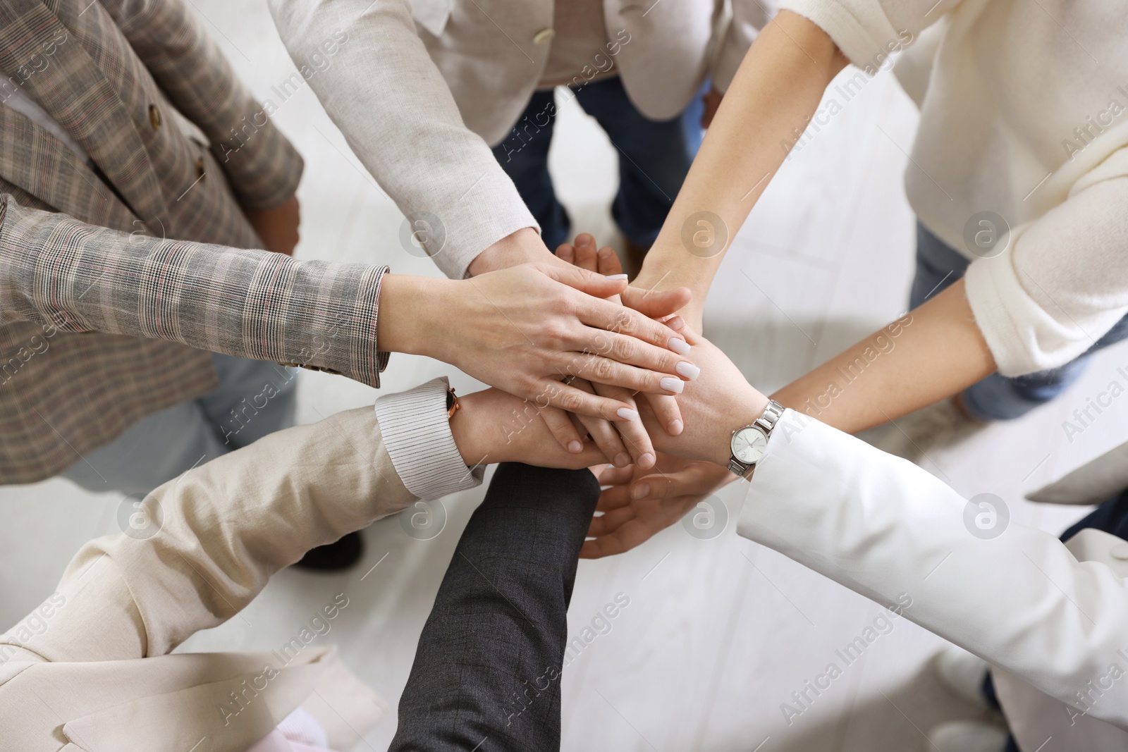 Photo of Unity concept. People holding hands together indoors, top view