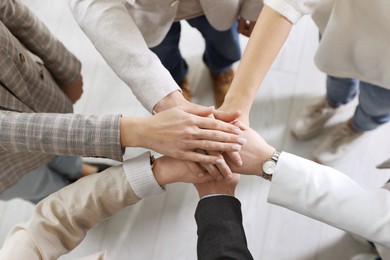 Unity concept. People holding hands together indoors, top view