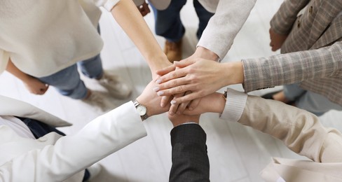 Unity concept. People holding hands together indoors, top view