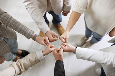 Photo of Unity concept. People holding fists together indoors, top view