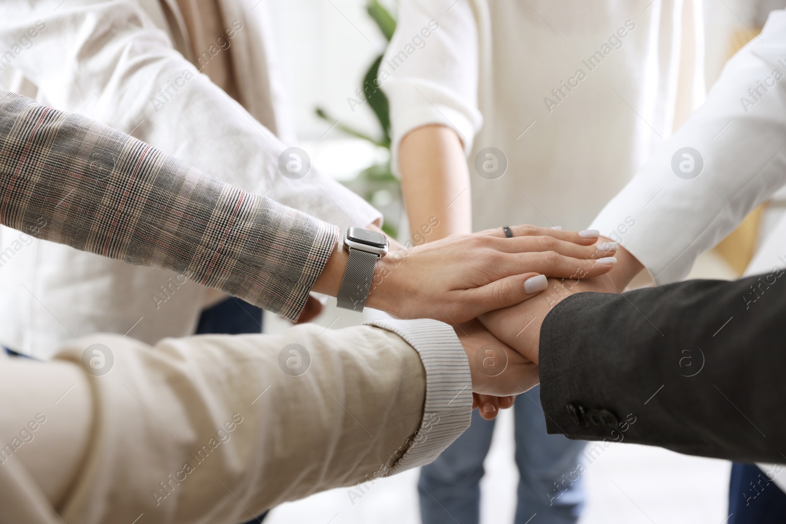 Photo of Unity concept. People holding hands together indoors, closeup