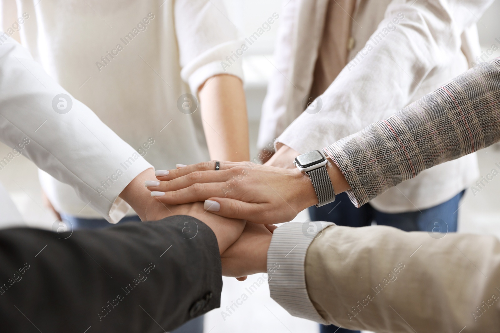 Photo of Unity concept. People holding hands together indoors, closeup