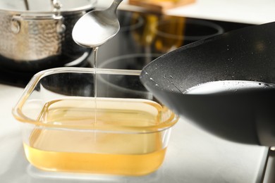 Photo of Pouring used cooking oil at white countertop, closeup