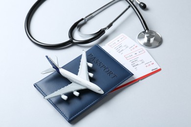 Photo of Medical tourism. Stethoscope, plane model, passport and flight tickets on light blue background