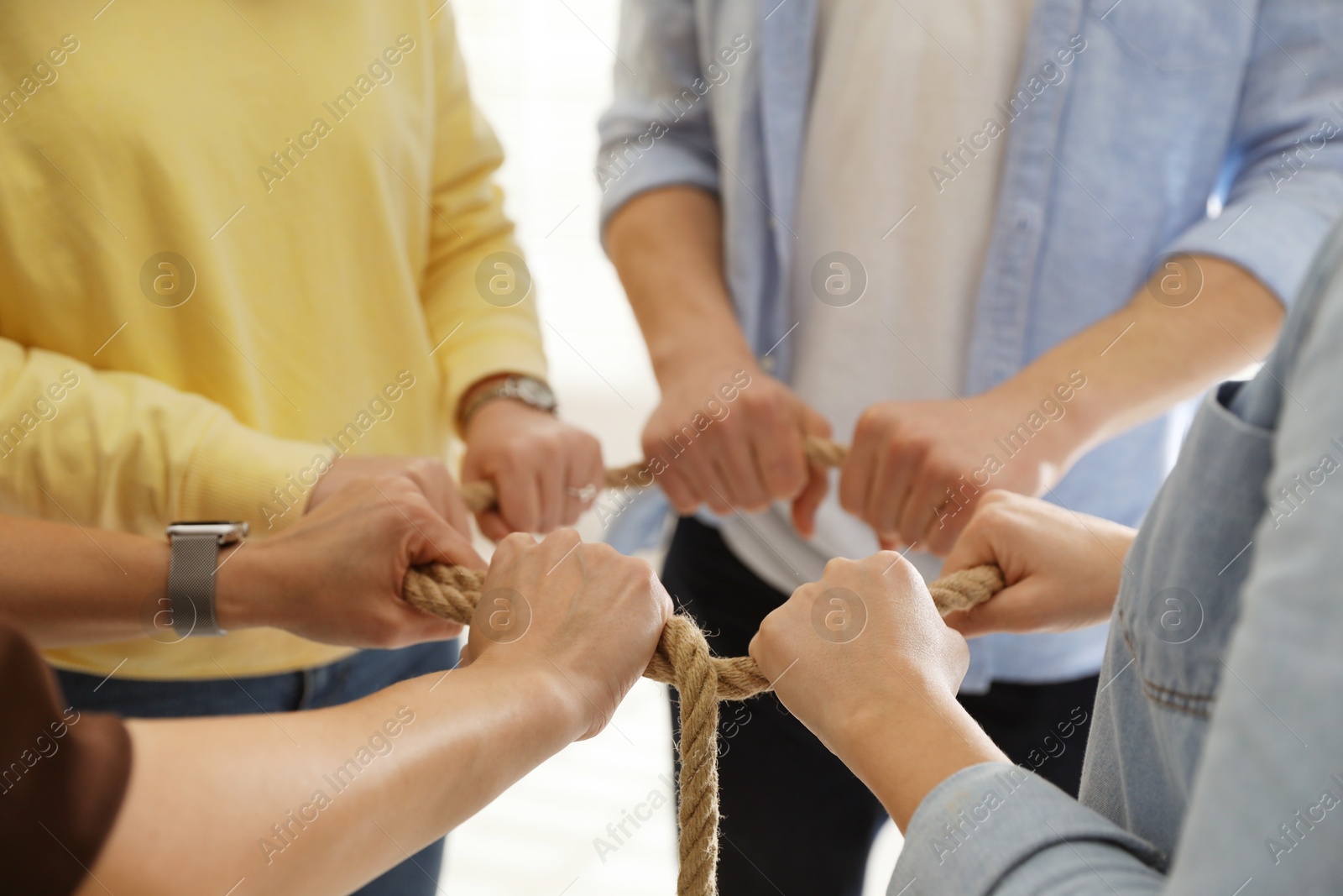 Photo of Unity concept. People holding rope together indoors, closeup