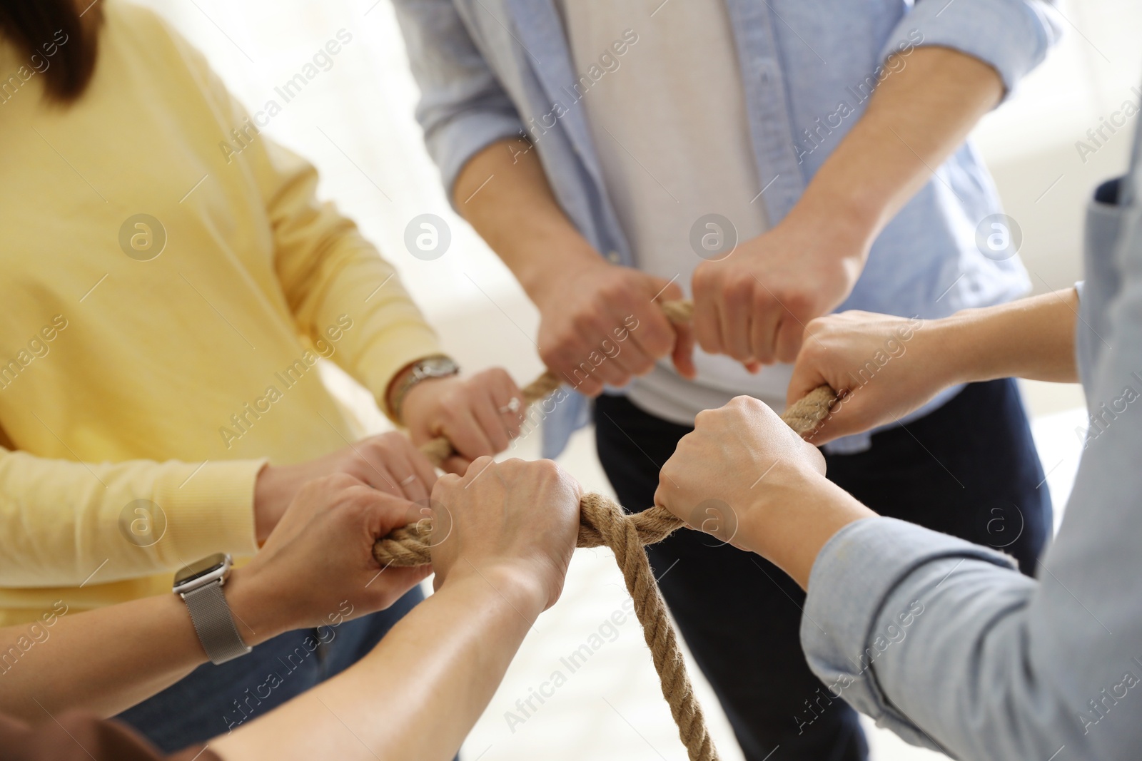 Photo of Unity concept. People holding rope together indoors, closeup