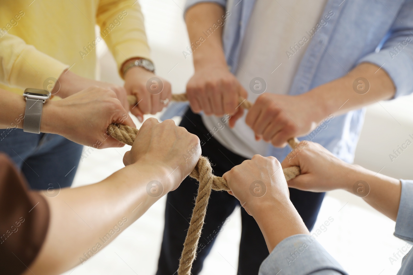 Photo of Unity concept. People holding rope together indoors, closeup