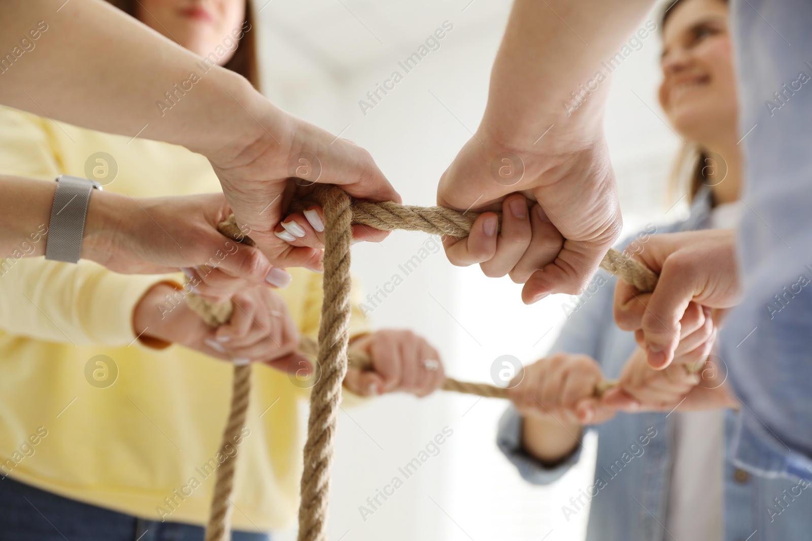 Photo of Unity concept. People holding rope together indoors, closeup