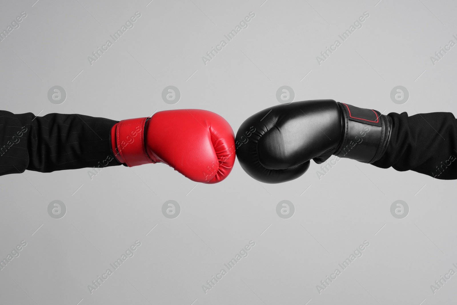 Photo of Business competition. Women in boxing gloves on grey background, closeup