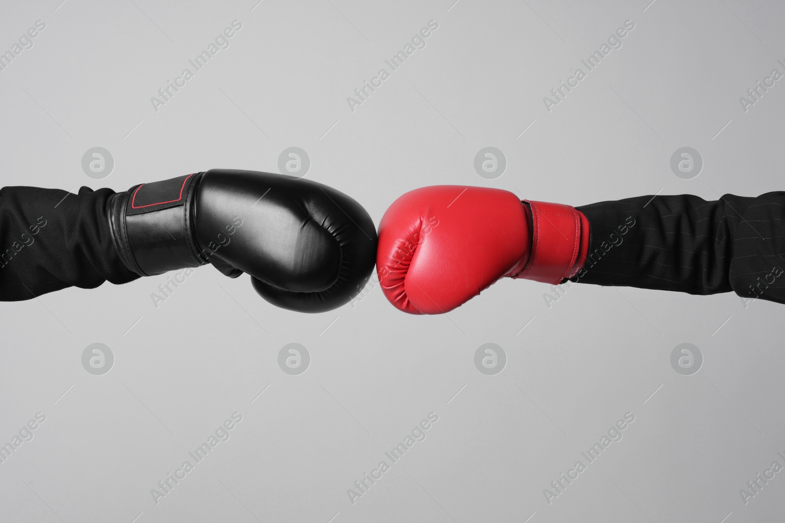 Photo of Business competition. Women in boxing gloves on grey background, closeup