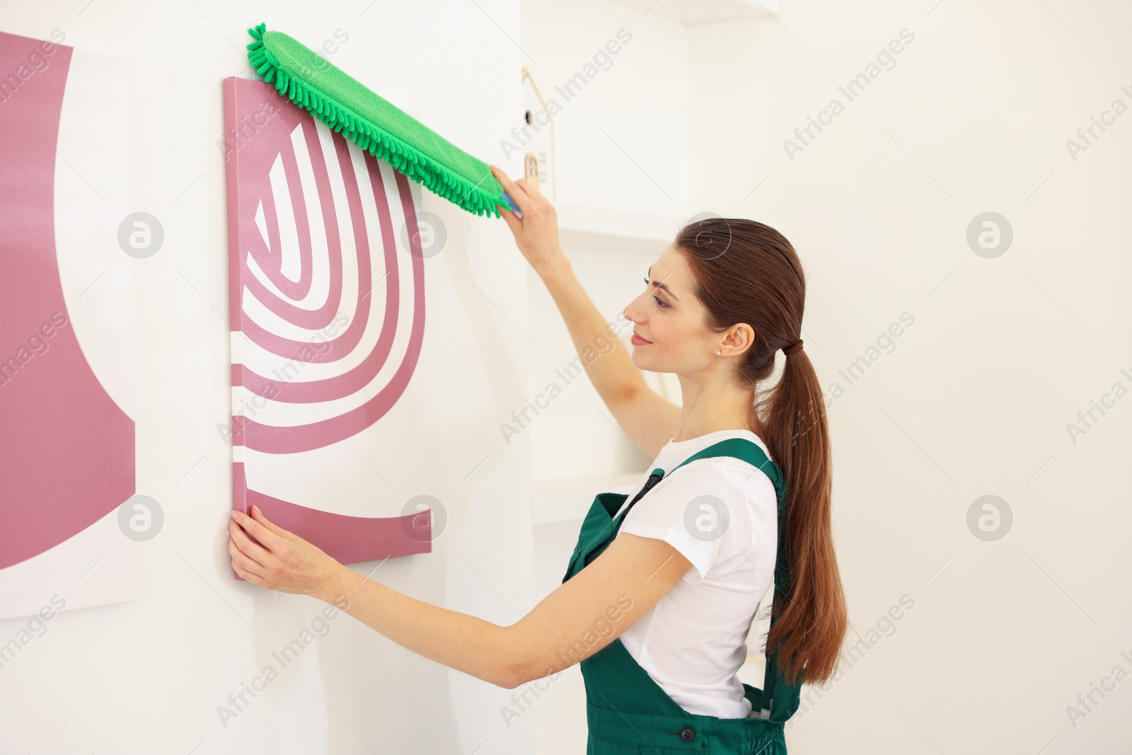 Photo of Professional janitor cleaning dust off picture indoors