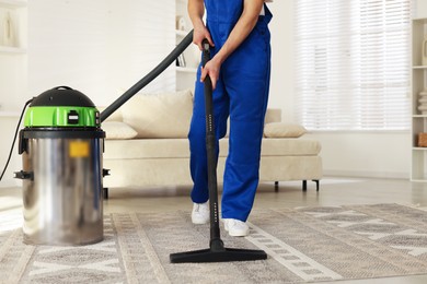 Photo of Cleaning service worker vacuuming rug with professional hoover at home, closeup