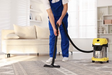 Photo of Cleaning service worker vacuuming rug with professional hoover at home, closeup