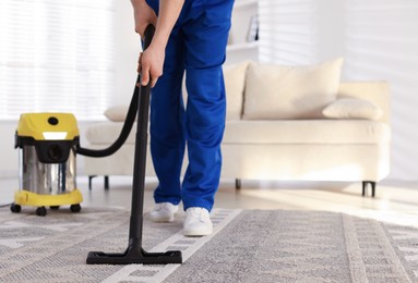 Photo of Cleaning service worker vacuuming rug with professional hoover at home, closeup