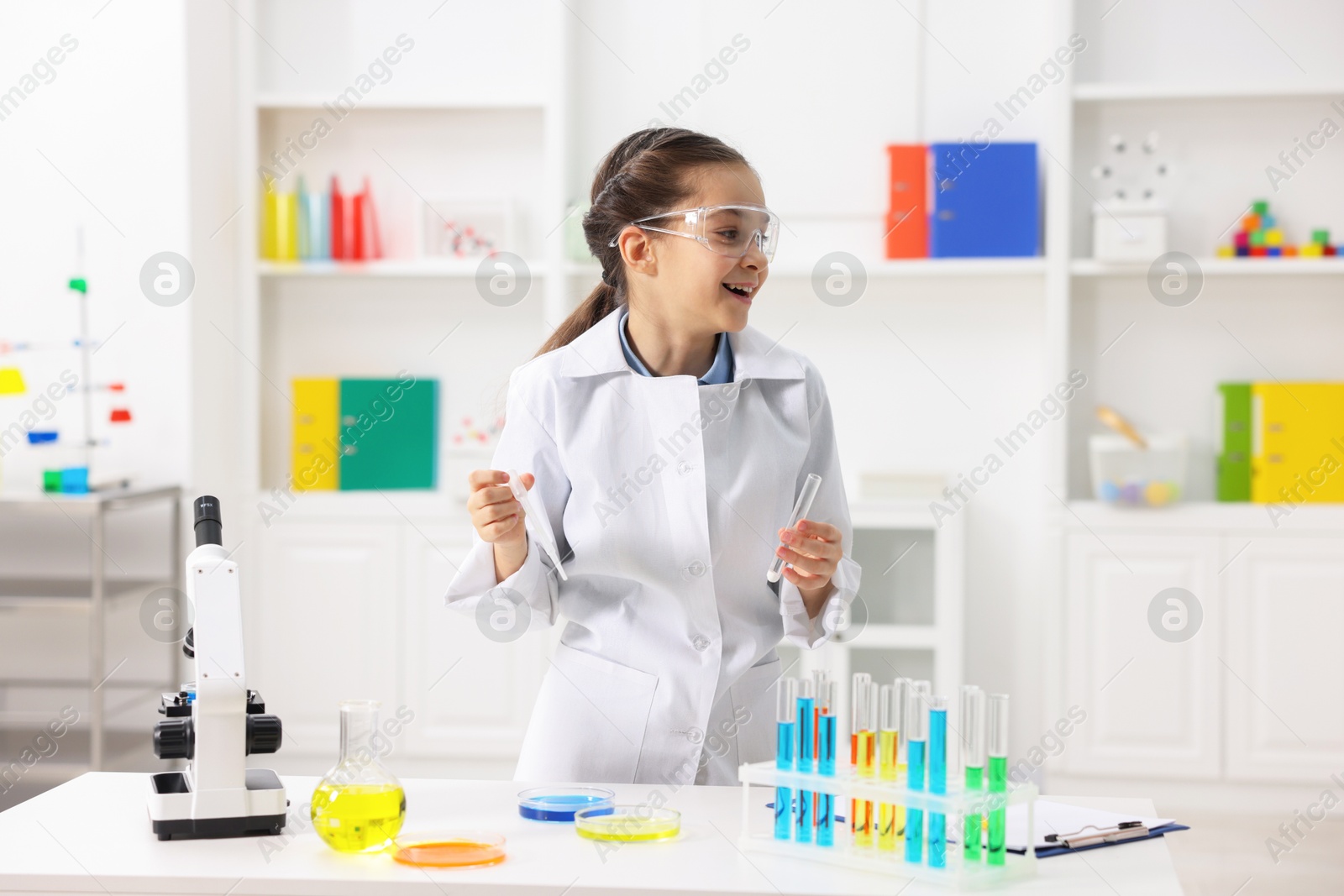 Photo of Little girl doing chemical experiment at desk indoors