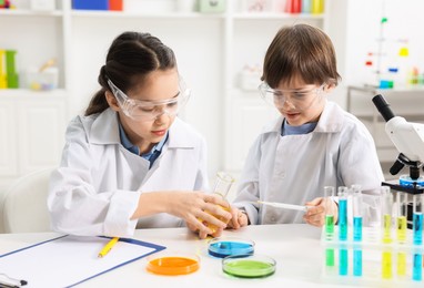 Children doing chemical experiment at desk indoors