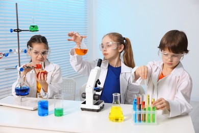 Children doing chemical experiment at desk indoors