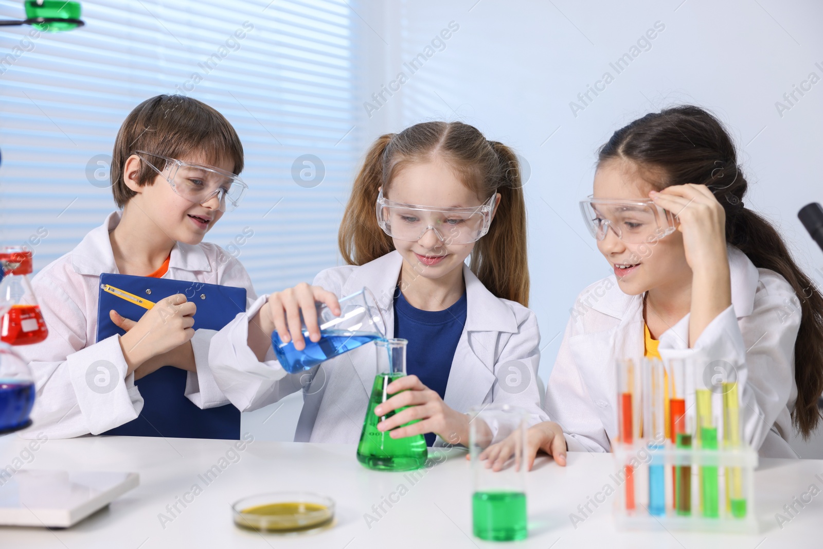 Photo of Children doing chemical experiment at desk indoors