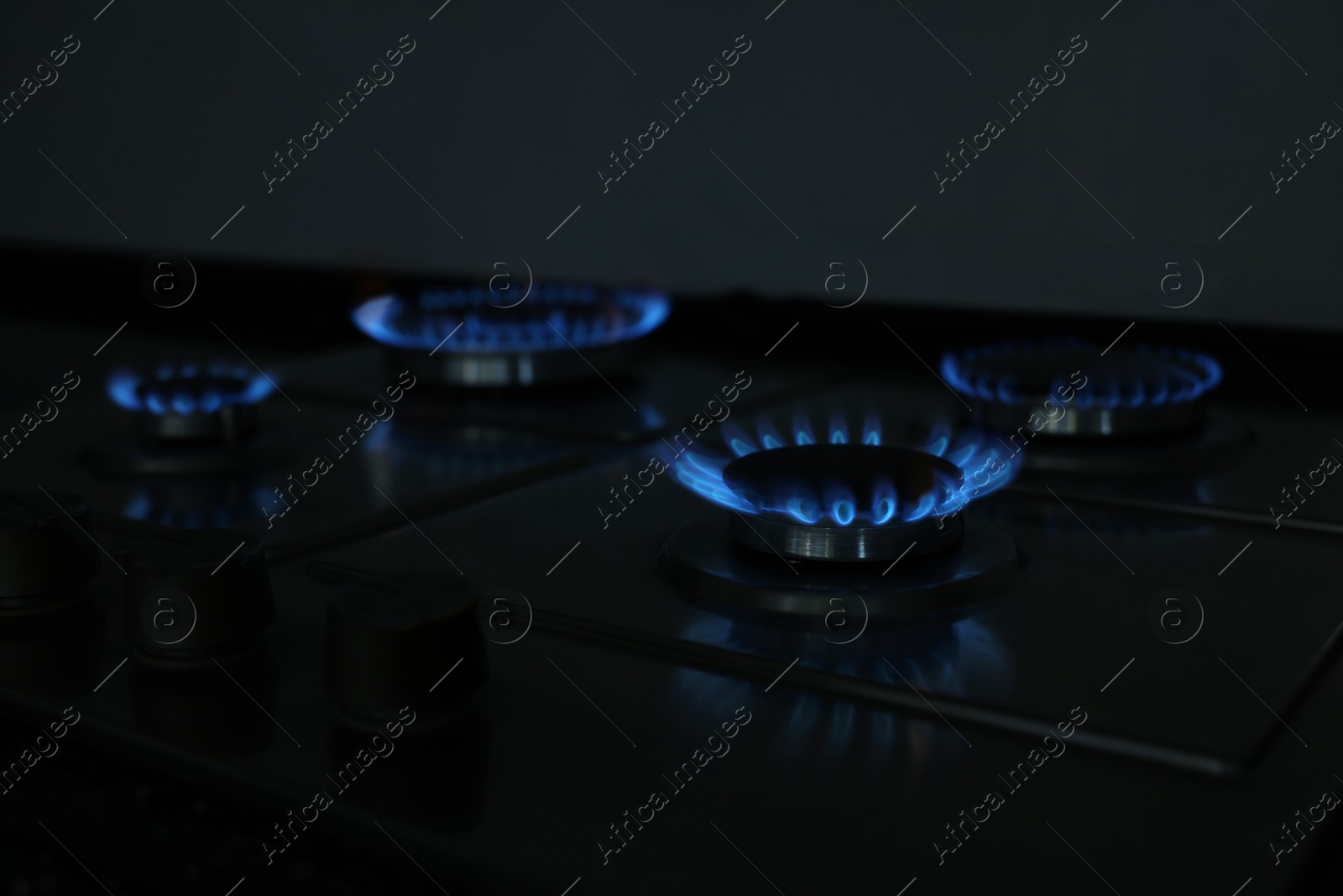 Photo of Gas burners with blue flame on stove, closeup