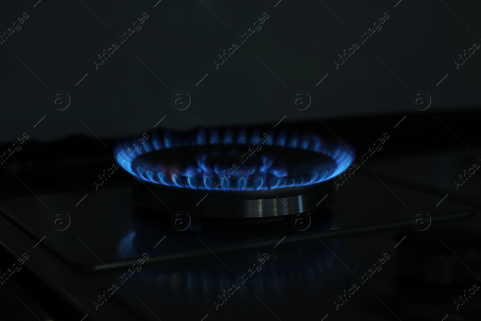 Photo of Gas burner with blue flame on stove, closeup