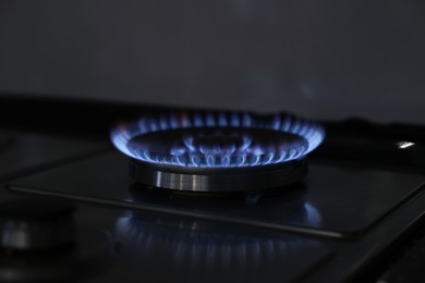 Photo of Gas burner with blue flame on stove, closeup