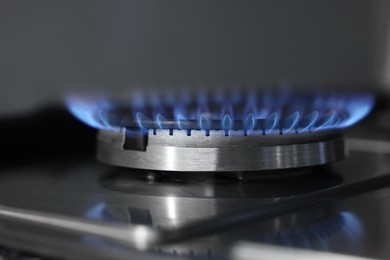 Photo of Gas burner with blue flame on stove, closeup