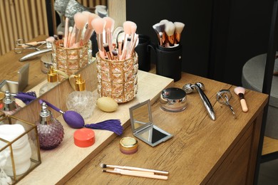 Photo of Makeup room. Different beauty products on wooden dressing table indoors