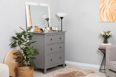 Photo of Makeup room. Mirror, dresser, different beauty products and houseplant indoors