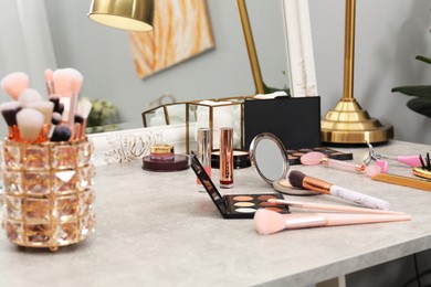 Photo of Makeup room. Different beauty products on grey dressing table and mirror indoors, closeup