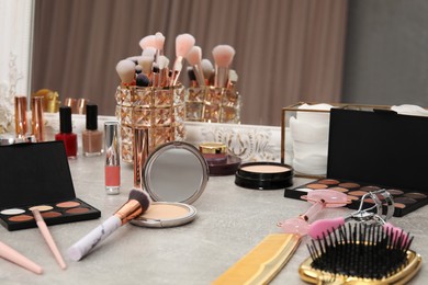 Photo of Makeup room. Different beauty products on grey dressing table and mirror indoors, closeup