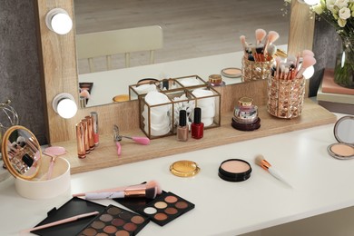 Photo of Makeup room. Different beauty products on white dressing table and mirror indoors