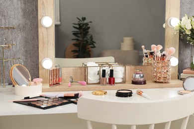 Photo of Makeup room. Different beauty products on dressing table, mirror and chair indoors