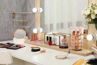 Photo of Makeup room. Different beauty products on white dressing table and mirror indoors