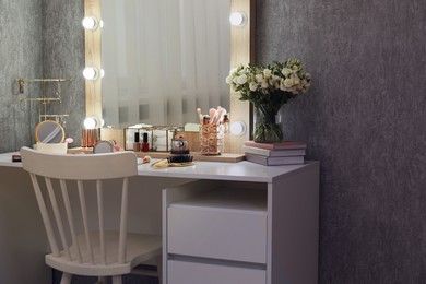 Photo of Makeup room. Mirror, dressing table, different beauty products and chair indoors