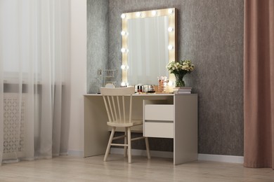 Photo of Makeup room. Mirror, dressing table, different beauty products and chair indoors