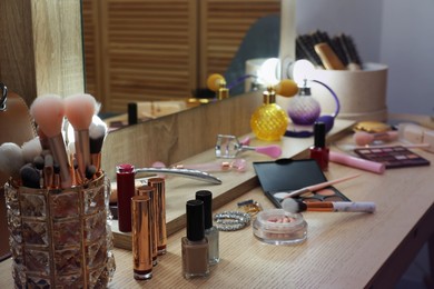 Photo of Makeup room. Different beauty products on wooden dressing table and mirror indoors, closeup