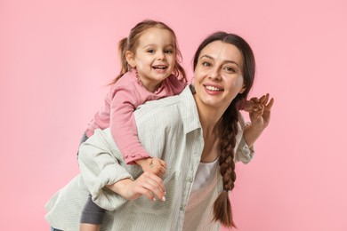 Photo of Portrait of happy mother and her cute daughter on pink background