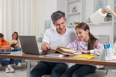 Photo of Parents and their children doing homework at home