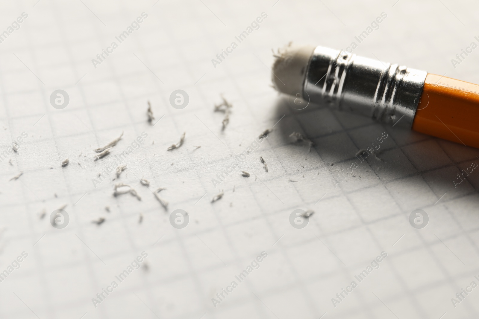 Photo of Pencil with eraser and scraps on white sheet of paper, closeup