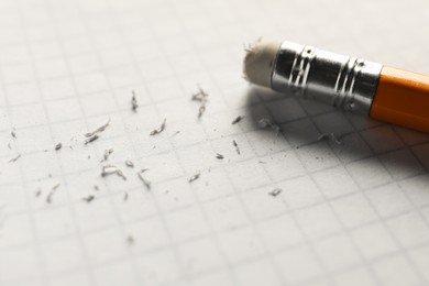 Photo of Pencil with eraser and scraps on white sheet of paper, closeup