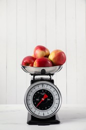 Photo of Retro mechanical kitchen scale with apples on white marble table