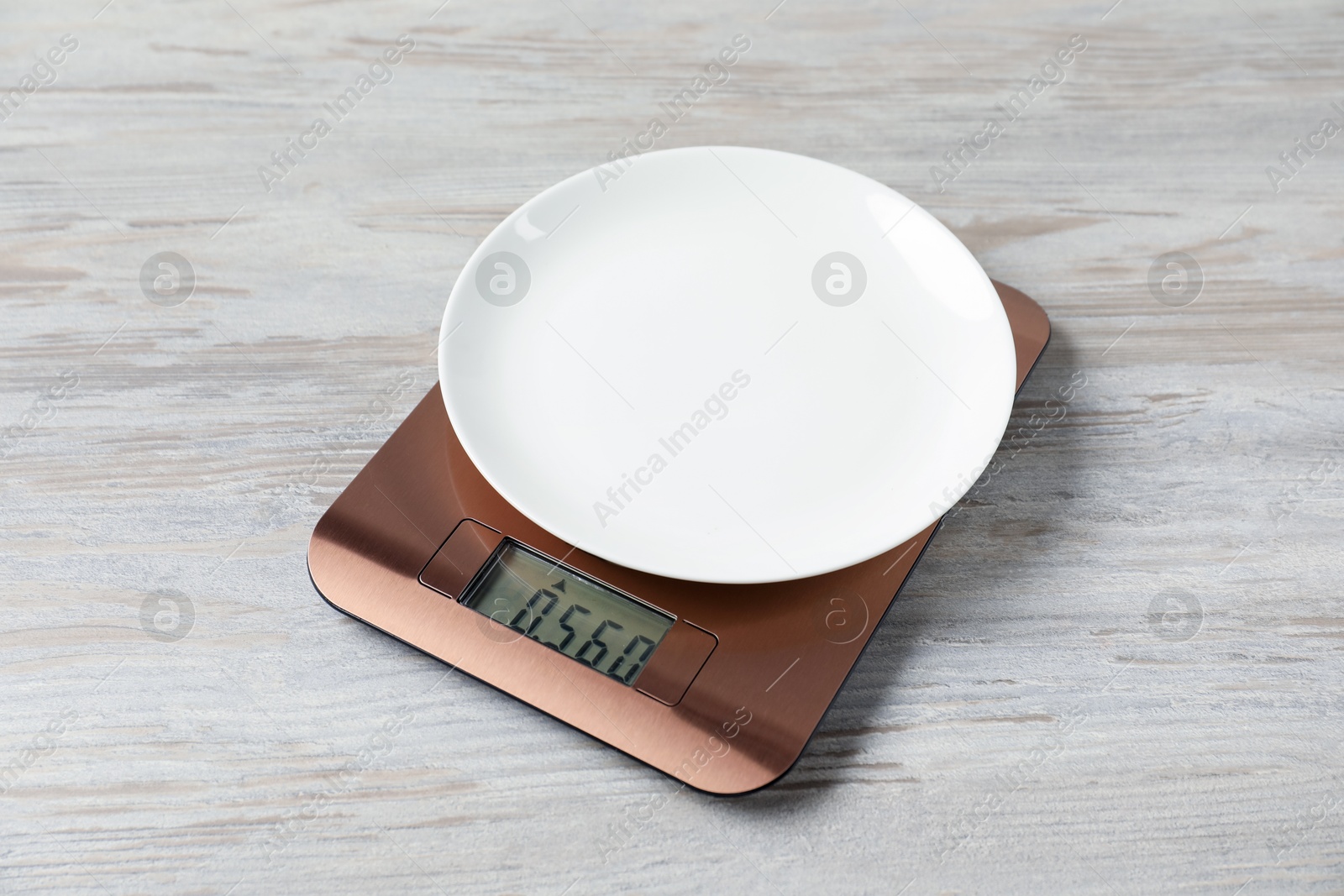 Photo of Modern electronic kitchen scale with plate on wooden table