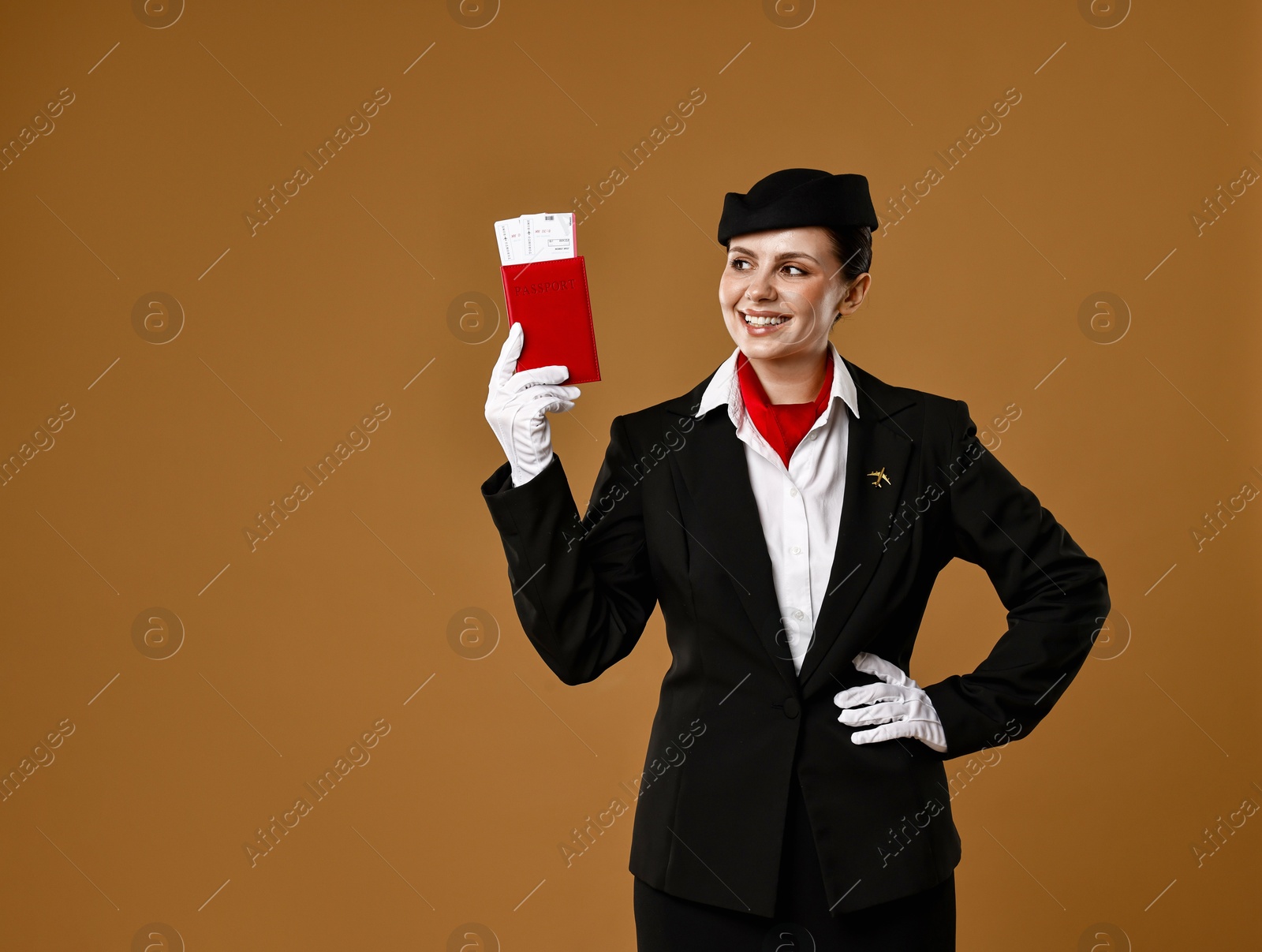 Photo of Happy stewardess holding passport with flight tickets on brown background. Space for text