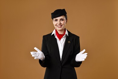 Smiling flight attendant demonstrating safety instruction on brown background