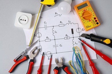 Photo of Different electrical tools and circuit diagram on grey background, flat lay