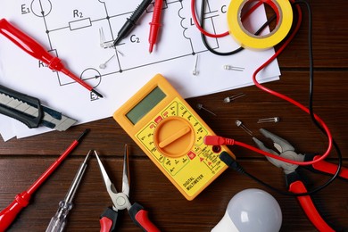 Photo of Different electrical tools and circuit diagram on wooden table, flat lay