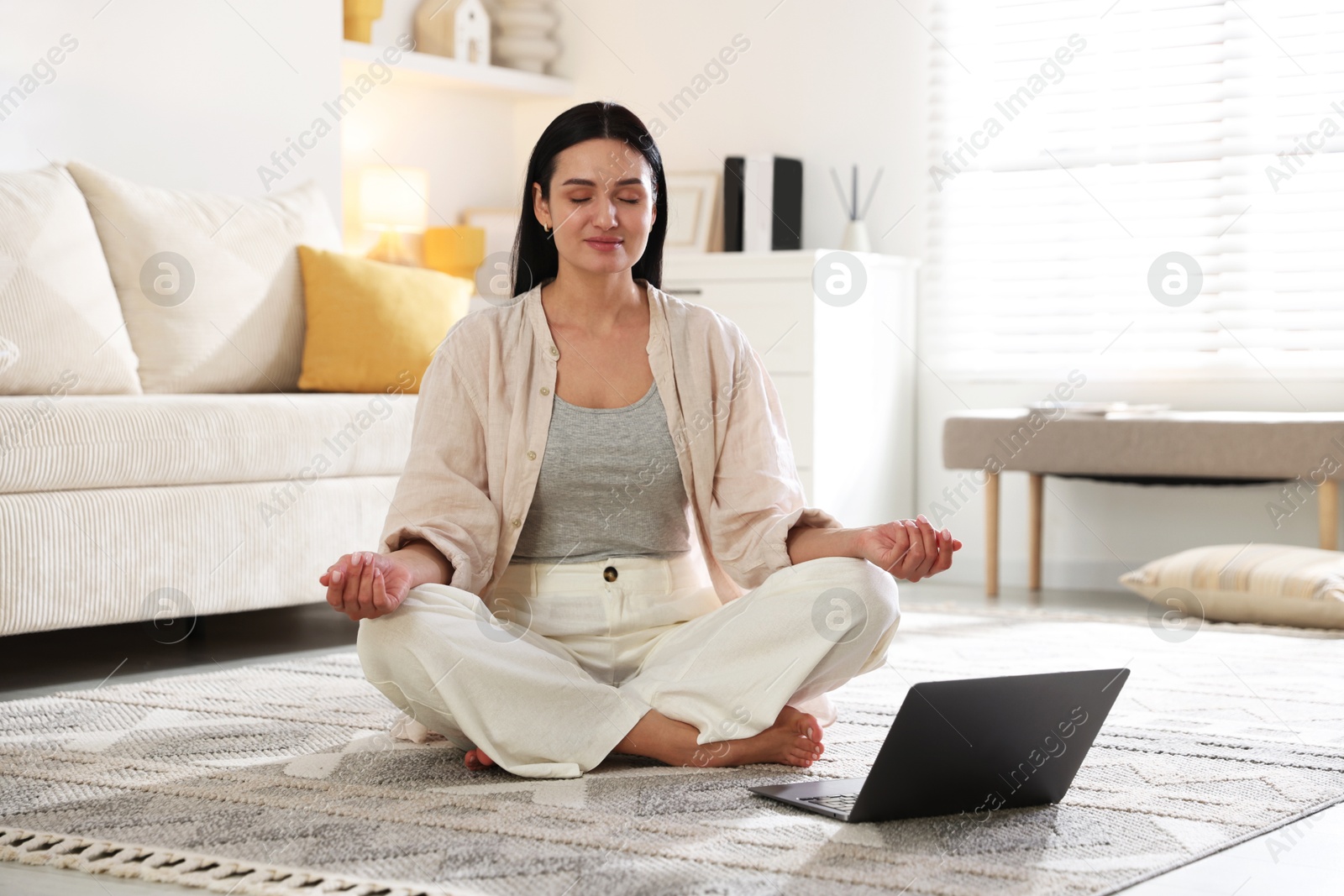 Photo of Woman with laptop meditating on floor at home